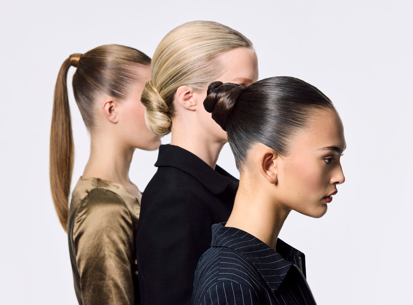 Three women with styled hair in ponytails against a plain background